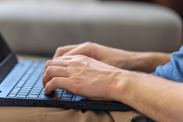 Male hands are typing something on the laptop keyboard. The concept of remote work from home. IT professions, online training