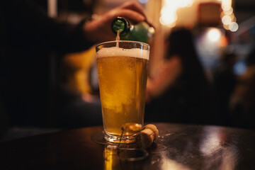 Beer glass on a wooden table. Pouring a fresh beer, pub scene. 