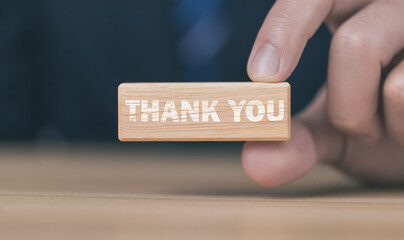 Businessman holding wooden block showing a message with word thank you letter	
