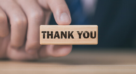 Businessman holding wooden block showing a message with word thank you letter	
