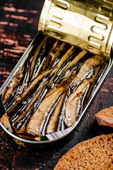 An open tin jar of sprats on the table. 