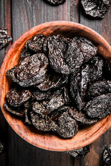 Prunes in a plate on a wooden background.