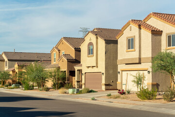 Fototapeta na wymiar Row of modern suburban houses in a desert region in southwestern north america in Arizona with visible trees