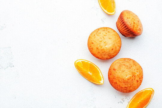 Appetizing orange muffins or cupcakes on white table background, winter homemade pastries, top view