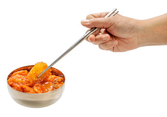 Hand using chopsticks to pick up Kimchi Korean pickle seasoning in metal bowl isolated on white background, Spicy Kimchi on white 