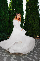 beautiful bride in a white delicate dress dances and spins in the park. 