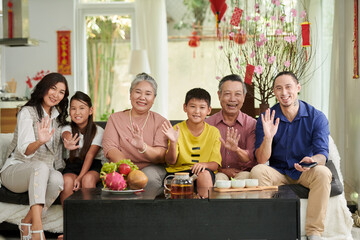 Happy big family having tea and fresh fruits at home when celebrating Tet