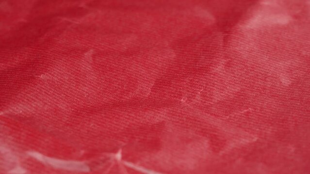 Crumpled red gift wrapping paper texture close up. Abstract background. Rotation