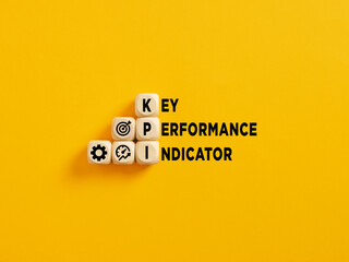 The acronym KPI and Key Performance Indicator text on wooden cubes on yellow background.
