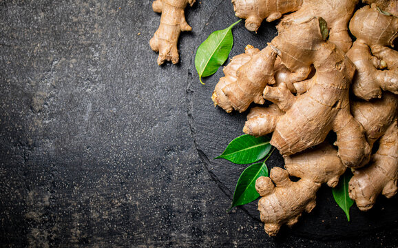 Fresh ginger with leaves on a stone board. 