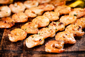 Grilled shrimp on a wooden cutting board.