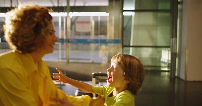 Caring mother lifts her son in her arms. Child runs to his mother to hug. The long-awaited meeting of mother and son at station. The woman met her son at the railway station to go on vacation together