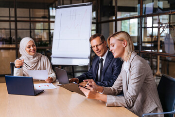 Multiracial group of corporate businesspeople working in a business office - Multiethnic businessmen and businesswomen meeting in the office in Dubai, UAE