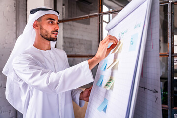 Arab businessman wearing emirates kandora working at board in the office