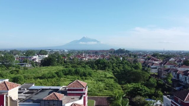 Yogyakarta, Indonesia - January 21, 2023 : Aerial view of a residence with Mount Merapi in the morning in the background. Shot forwards