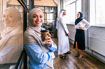 Middle-eastern group of corporate businesspeople working in a business office - Arab businessman with kandora and businesswomen with abaya meeting in the office in Dubai, UAE