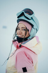 Female snowboarder in outdoors smiling in winter clothing, helmet, snow glasses.