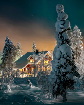 Beautiful winter night landscape with deep snow covered trees and wooden hut in foreground. (high ISO image)