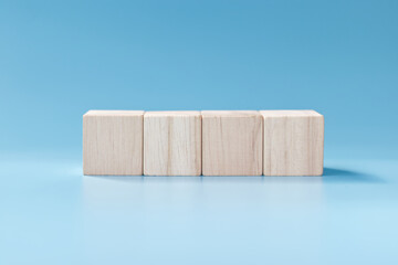 four blank wooden blocks on blue background.