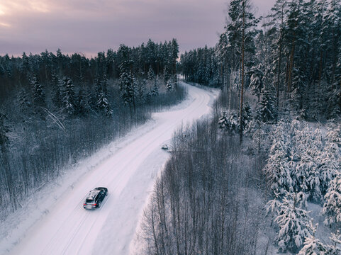 Beautiful winter sunrise in deep forest from above with a road and a car, birds eye view