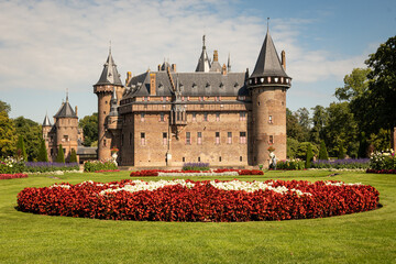 outside of Kasteel De Haar Dutch medieval castle with floral garden on sunny summer day. Flowers match colour of Utrecht Netherlands where historic building with European architecture is located
