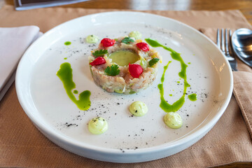 salad of various ingredients is beautifully arranged in the form of a ring on a white plate.