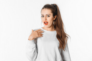 Surprised beautiful young woman looking at camera in excitement standing against white background....