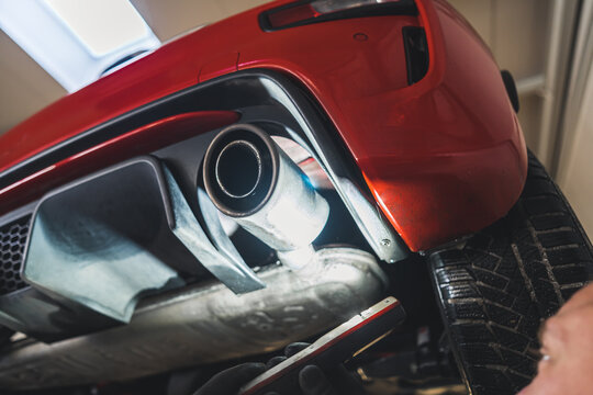 A close shot of a exhaust pipe and a red car's rear, Repair shop concept. High quality photo