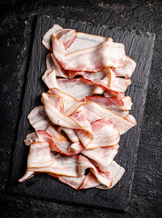 Pieces of fresh bacon on a stone board. 