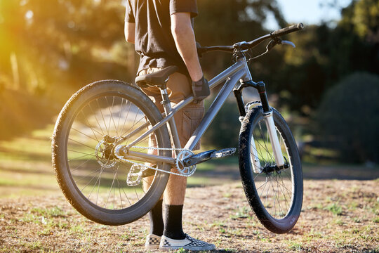 Bicycle, fitness and summer with a sports man outdoor in nature for leisure or recreation in summer. Back, bike and exercise with a male athlete standing on an open green field carrying his transport