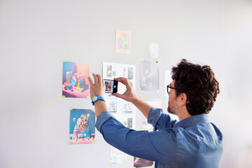 Man taking photo of wall pictures