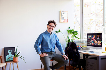 Cheerful businessman sitting in office against window