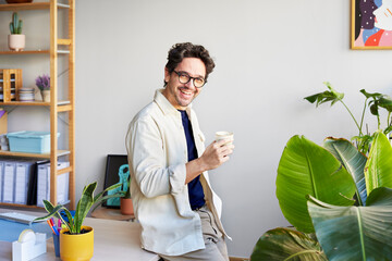 Smiling man having coffee in creative workspace