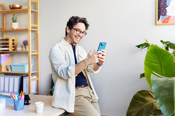 Cheerful man using smartphone at home office