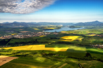 Beautiful country landscape with green, yellow fields and lake at background. Liptov, Slovakia