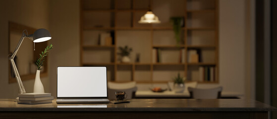 Workspace with laptop mockup, table lamp and decor on tabletop over blurred background