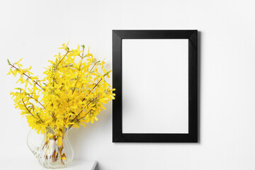 Portrait frame mockup on white wall interior with yellow spring flowers in vase, blank mockup with copy space