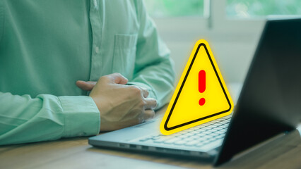 Adult man using computer laptop with triangle caution warning sign for notification error. Computer...