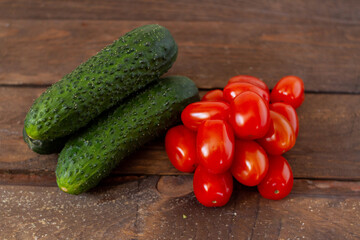 Cucumbers, cherry tomatoes on wooden boards.