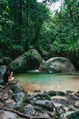 Woman crouching taking in the beauty of Mossman Gorge in far North Queensland.