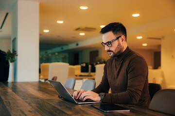 Adult male boss working on a new project over the laptop, sitting at the office.