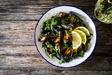 Cooked mussels with lemon and parsley on wooden table
