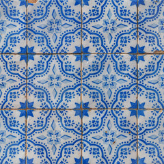 Damaged, faded, not corrected, vintage azulejos, glazed ceramic tiles with blue ornaments on building wall. Heritage Concept of traditional Portuguese art.