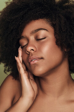 Young African American lady touching face during skincare procedure