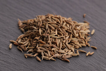 a bunch of natural dried cumin on a gray stone plate. side view