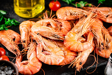 Boiled shrimp on a stone board with tomatoes and parsley.