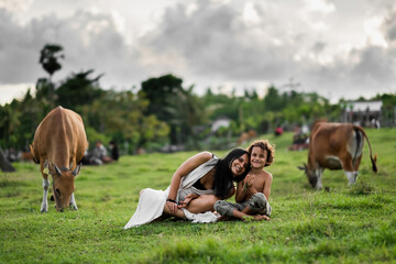 Happy mom and son hugging in the meadow, among the cows.