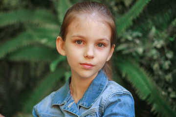 Portrait of a beautiful girl in nature in the park on a sunny day, the child smiles happily, close-up portrait, spring mood, a beautiful day outdoors.
