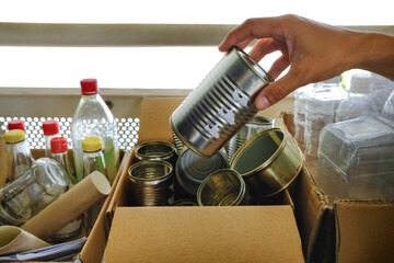 Man putting metal can into sorting boxes for recycling outside apartment flat. Zero waste sustainability concept. Recycling management - metal plastic glass bottles containers paper. Selective focus