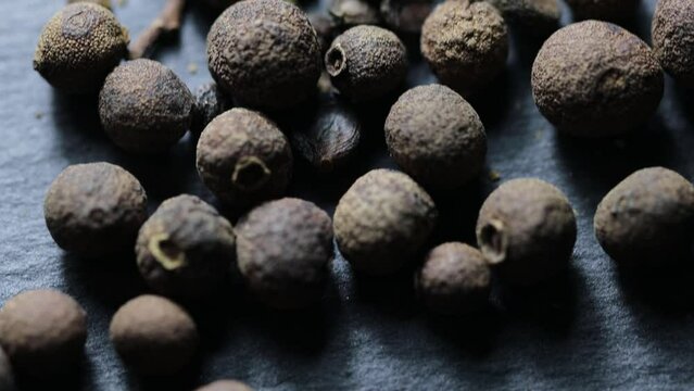 natural black peppercorns on a stone stand. vertical camera movement